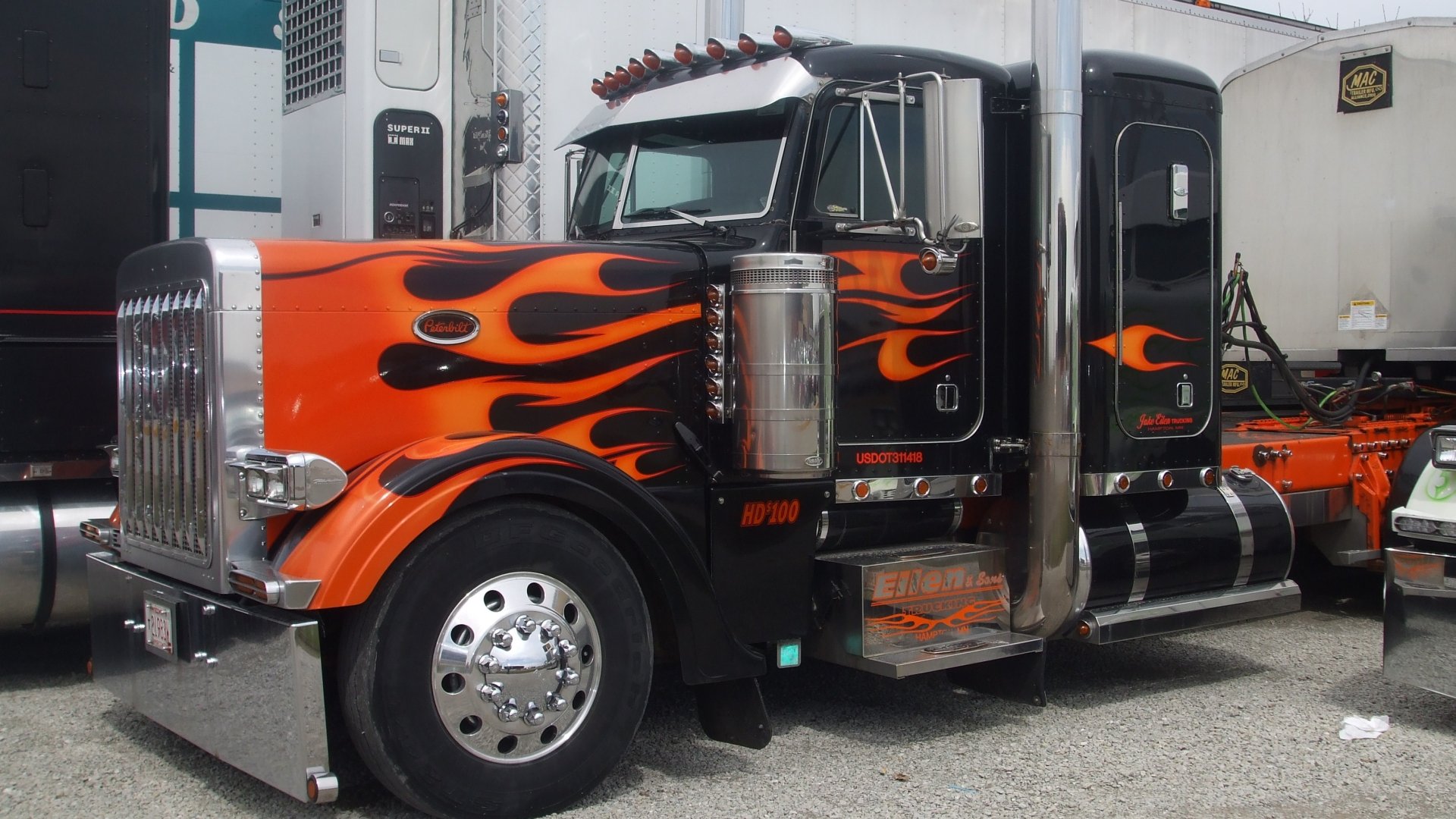A striking HD desktop wallpaper featuring a black and orange truck adorned with fiery flame graphics, showcasing its powerful presence and sleek design.