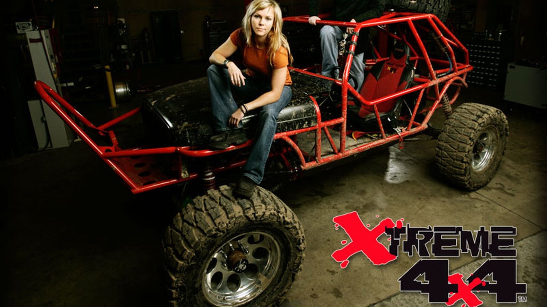 HD PC desktop wallpaper showing a red tubular off-road 4x4 vehicle with oversized tires in a garage, a person sitting on the hood, and Xtreme 4x4 logo visible.
