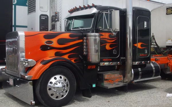 A striking HD desktop wallpaper featuring a black and orange truck adorned with fiery flame graphics, showcasing its powerful presence and sleek design.