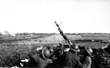 A historical black-and-white image of soldiers operating a machine gun, set against an expansive battlefield backdrop, making an impactful HD desktop wallpaper.
