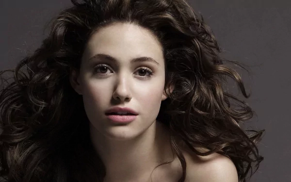 HD PC desktop wallpaper featuring a close-up portrait of celebrity Emmy Rossum with flowing dark hair against a dark background.