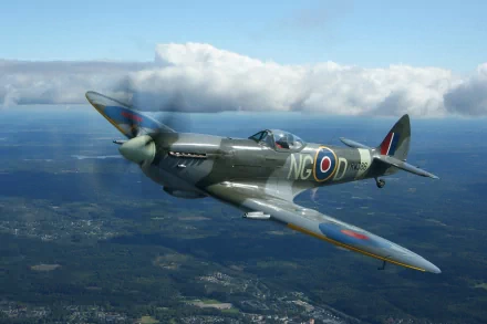 A Supermarine Spitfire Mk IX in flight, showcasing its military heritage against a backdrop of clouds and landscape. HD wallpaper featuring this iconic aircraft.