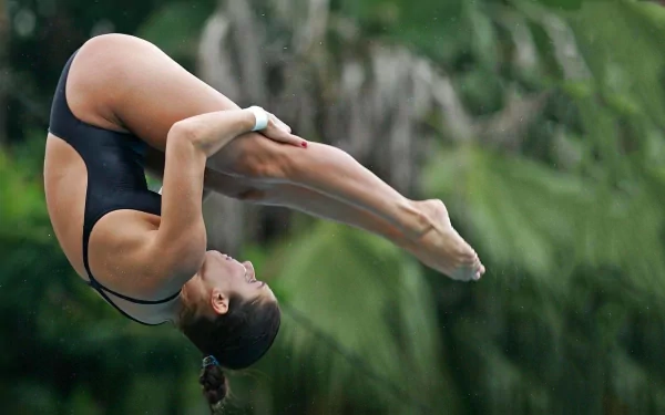 Athletic diver curled in a tight mid-tuck above blurred tropical foliage, dynamic sports HD PC desktop wallpaper and background.