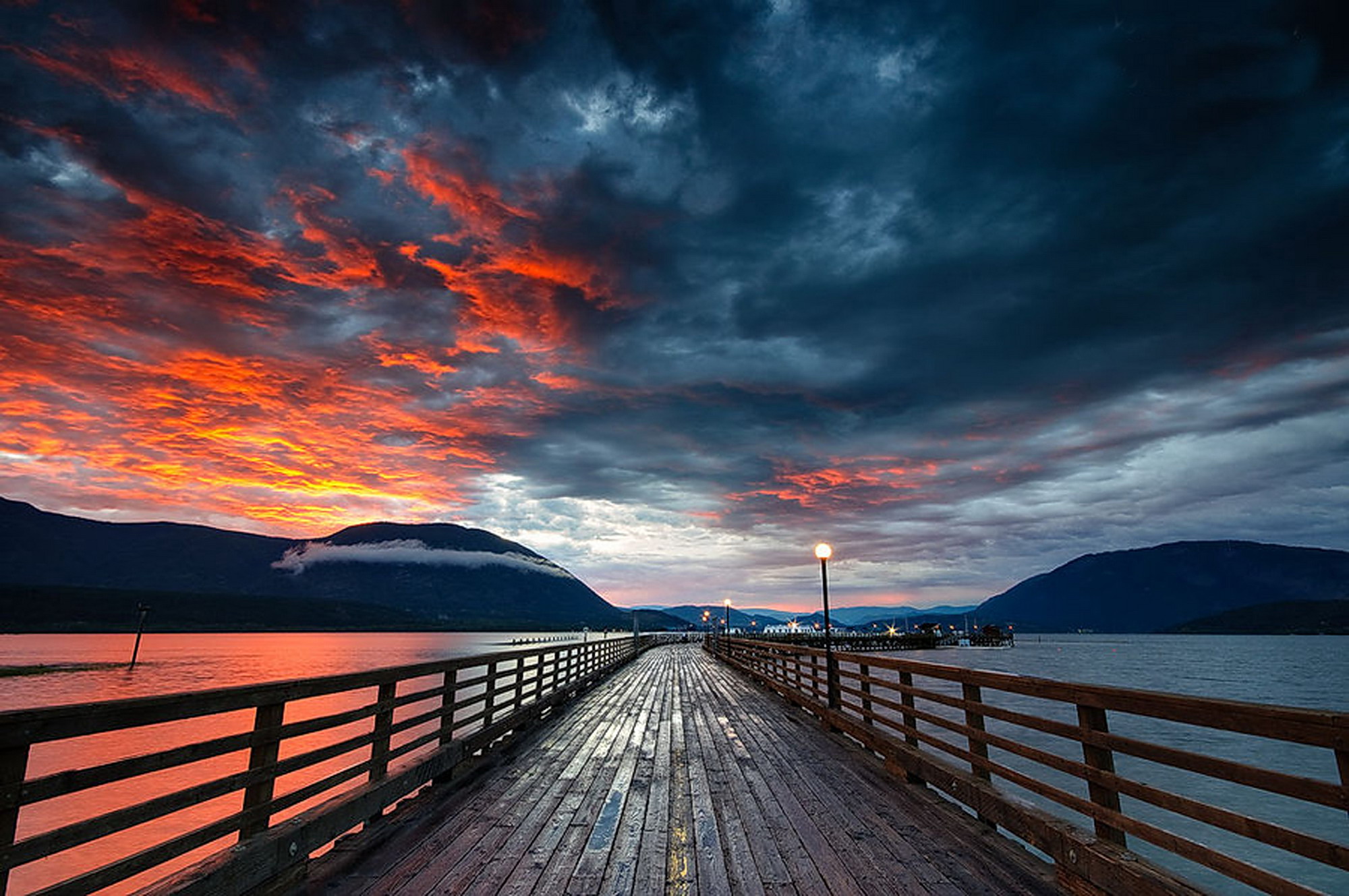 Stormy red sunset over ocean with wharf, captured by Viktoria Haack - a picturesque photography.