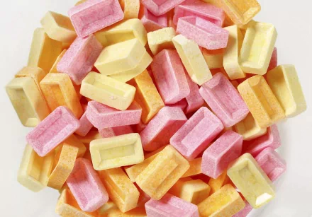 A vibrant assortment of colorful candy pieces in shades of pink, yellow, and orange, creating a delightful and eye-catching HD desktop wallpaper background.