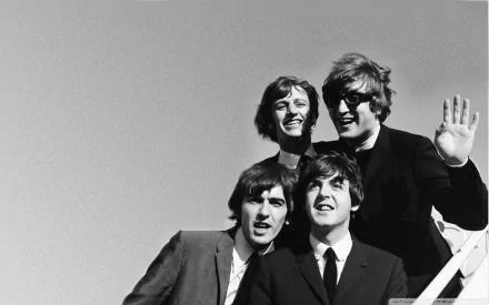 A classic black and white image featuring The Beatles, capturing their iconic spirit in a joyful moment. An HD desktop wallpaper celebrating their musical legacy.