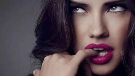 HD desktop wallpaper of a celebrity with striking makeup, tagged as Adriana Lima. The image showcases a close-up of the celebrity with lush lips and a contemplative expression.