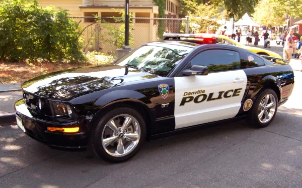 HD PC desktop wallpaper of a black-and-white police vehicle parked on a sunlit street, marked POLICE with rooftop lights.