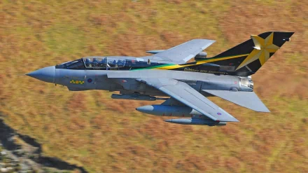 HD PC desktop wallpaper showing a military Panavia Tornado jet in low flight over moorland, cockpit, swept wings and tail with a yellow star emblem.