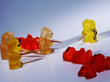 HD desktop wallpaper and background featuring gummy bears arranged in a playful battle scene with toothpicks, set against a minimalistic backdrop.