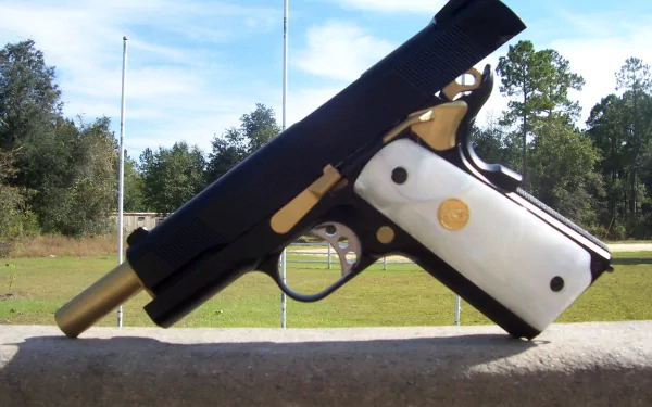 A high-definition desktop wallpaper featuring a Colt 1911 pistol, showcasing its intricate design with a striking gold and white grip against a natural outdoor background.