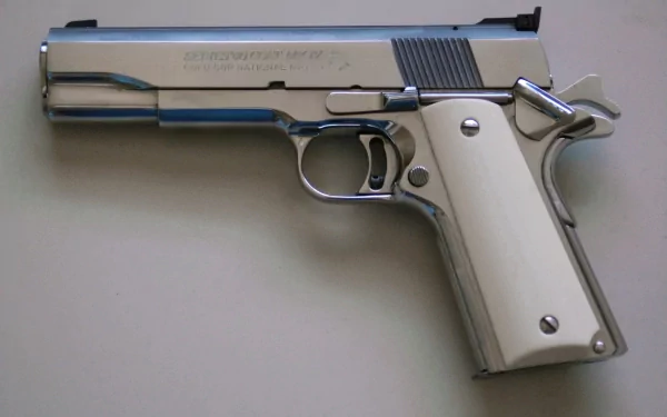 HD desktop wallpaper featuring a Colt .45 ACR 1911A1 man-made pistol with a polished silver finish and white grip against a neutral background.