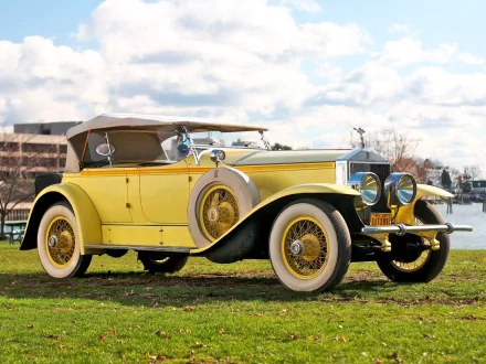 1926 Rolls-Royce convertible in vibrant yellow parked on grass by the water, showcasing classic luxury and vintage automotive design in HD quality.