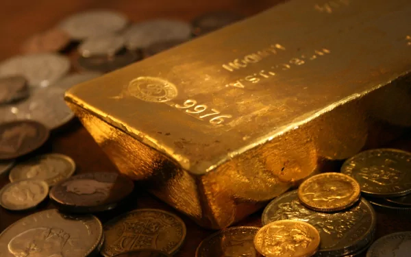 A shiny gold bar surrounded by various coins, creating a rich, man-made scene. This high-definition image serves as an elegant desktop wallpaper and background.