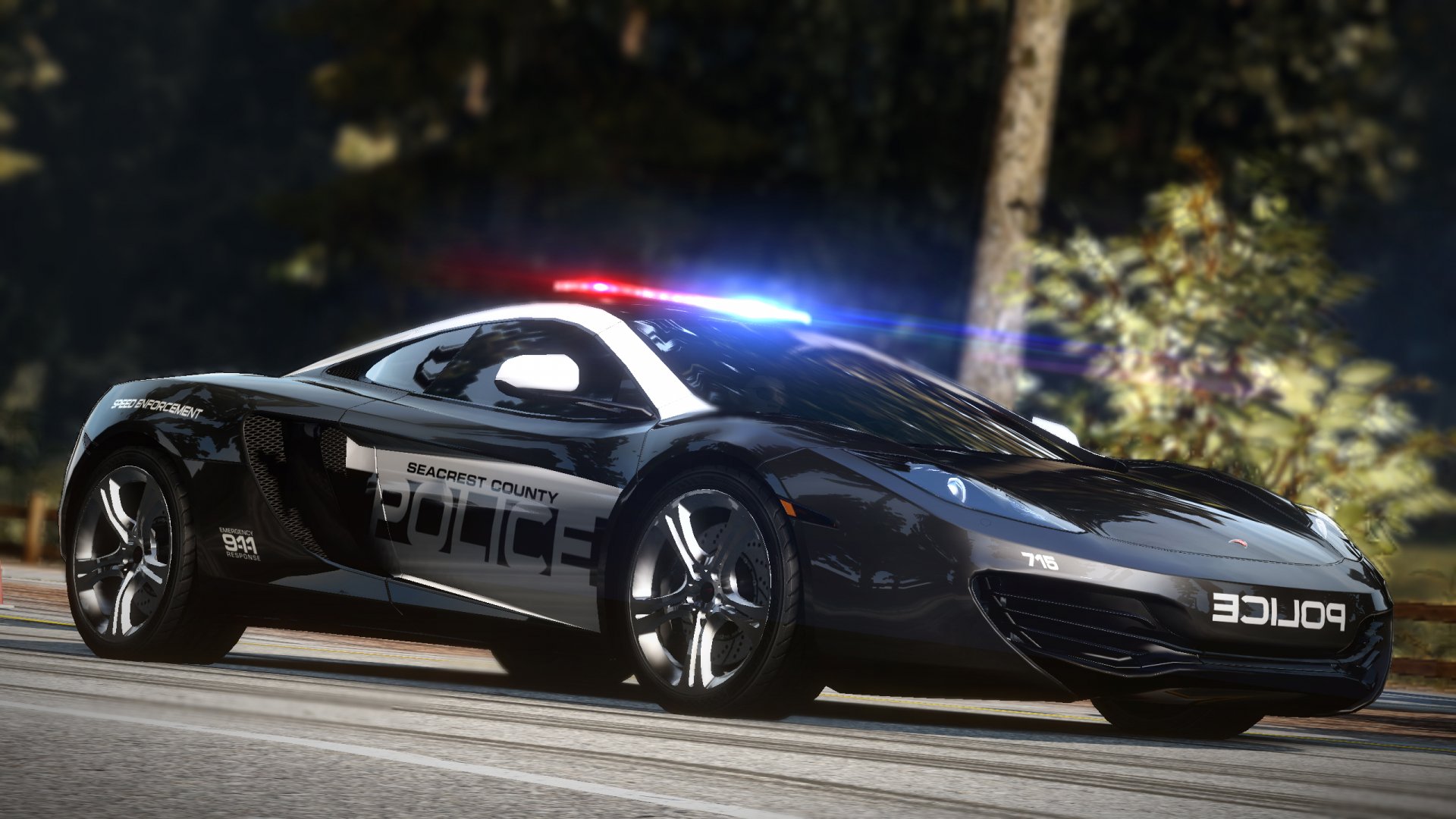 HD PC desktop wallpaper featuring a sleek police car from the video game Need For Speed: Hot Pursuit, with vibrant lighting and a blurred forest background.