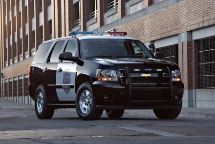 2K Quad HD PC desktop wallpaper of a black police SUV parked on an urban street in front of brick buildings, a vehicle-focused background image.