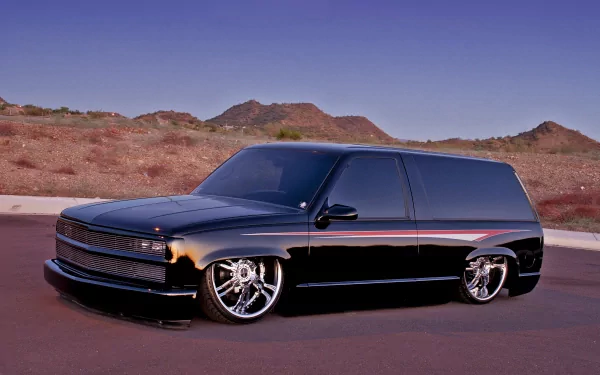 Black lowered custom truck vehicle with chrome wheels parked on a desert road against rocky mountains — 4K Ultra HD PC desktop wallpaper and background.