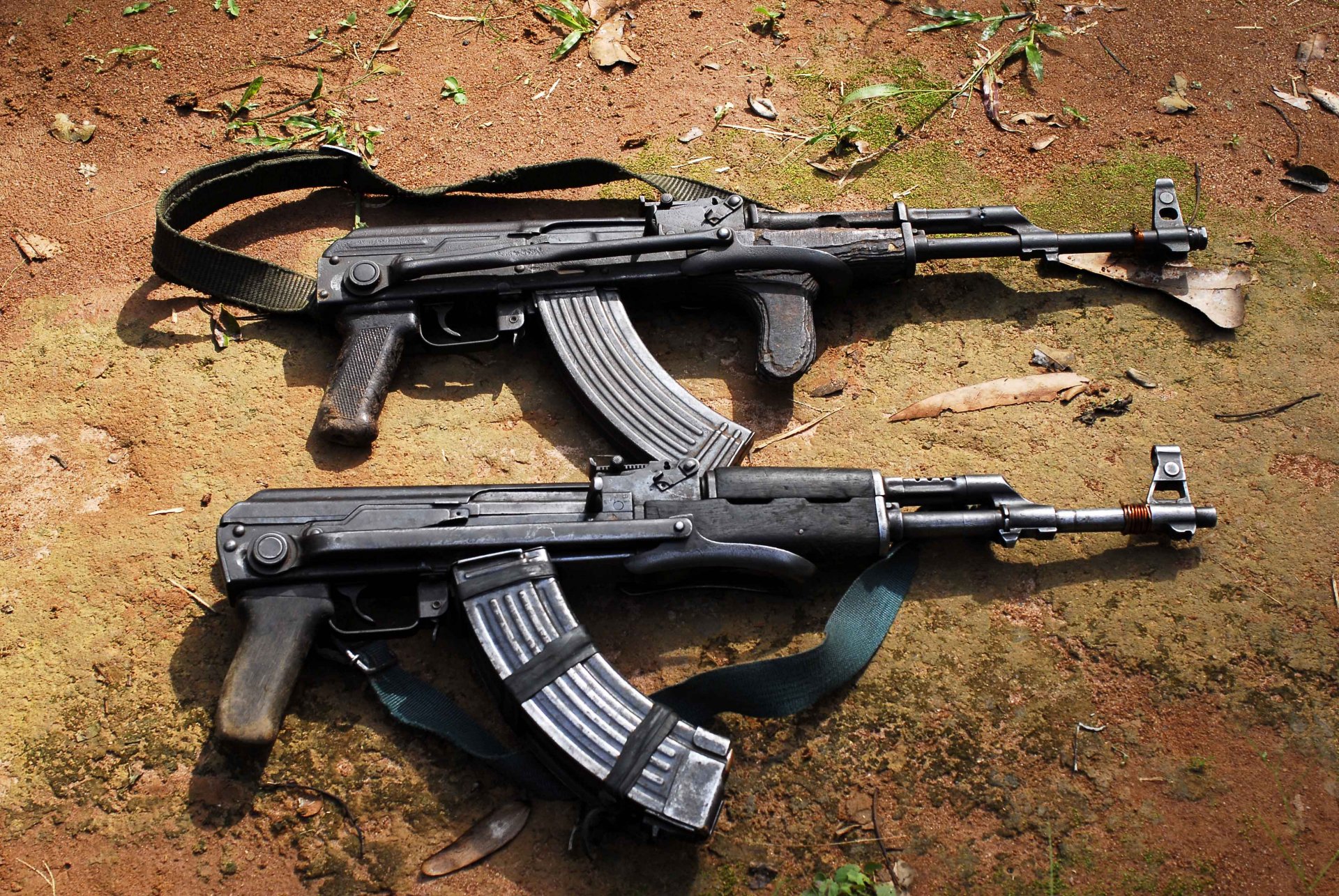 Two man-made AKM assault rifles lie crossed on the ground, captured in a detailed 4K Ultra HD PC desktop wallpaper and background image.