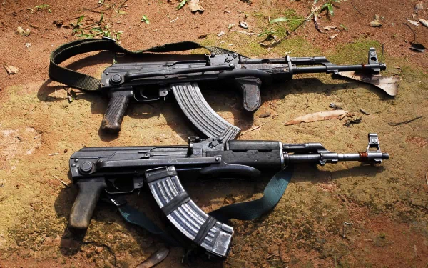 Two man-made AKM assault rifles lie crossed on the ground, captured in a detailed 4K Ultra HD PC desktop wallpaper and background image.
