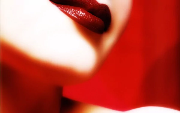 A close-up of a woman's lips adorned with deep red lipstick, set against a vibrant red background, creating a striking HD desktop wallpaper.
