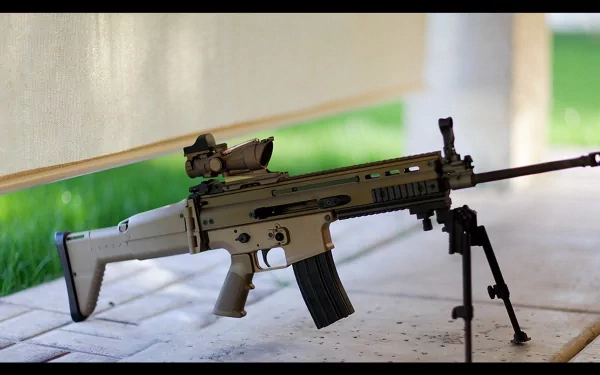 HD desktop wallpaper showcasing a man-made FN SCAR assault rifle resting on a bipod with a blurred outdoor background.