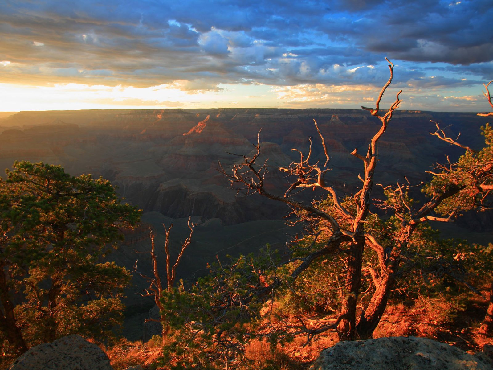 A breathtaking sunset over a canyon, highlighting the intricate landscape and vibrant colors of nature. This HD image captures a serene moment in a stunning outdoor setting.