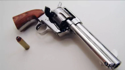 HD desktop wallpaper showing a man-made revolver with a wooden grip and a single bullet beside it on a plain white surface.