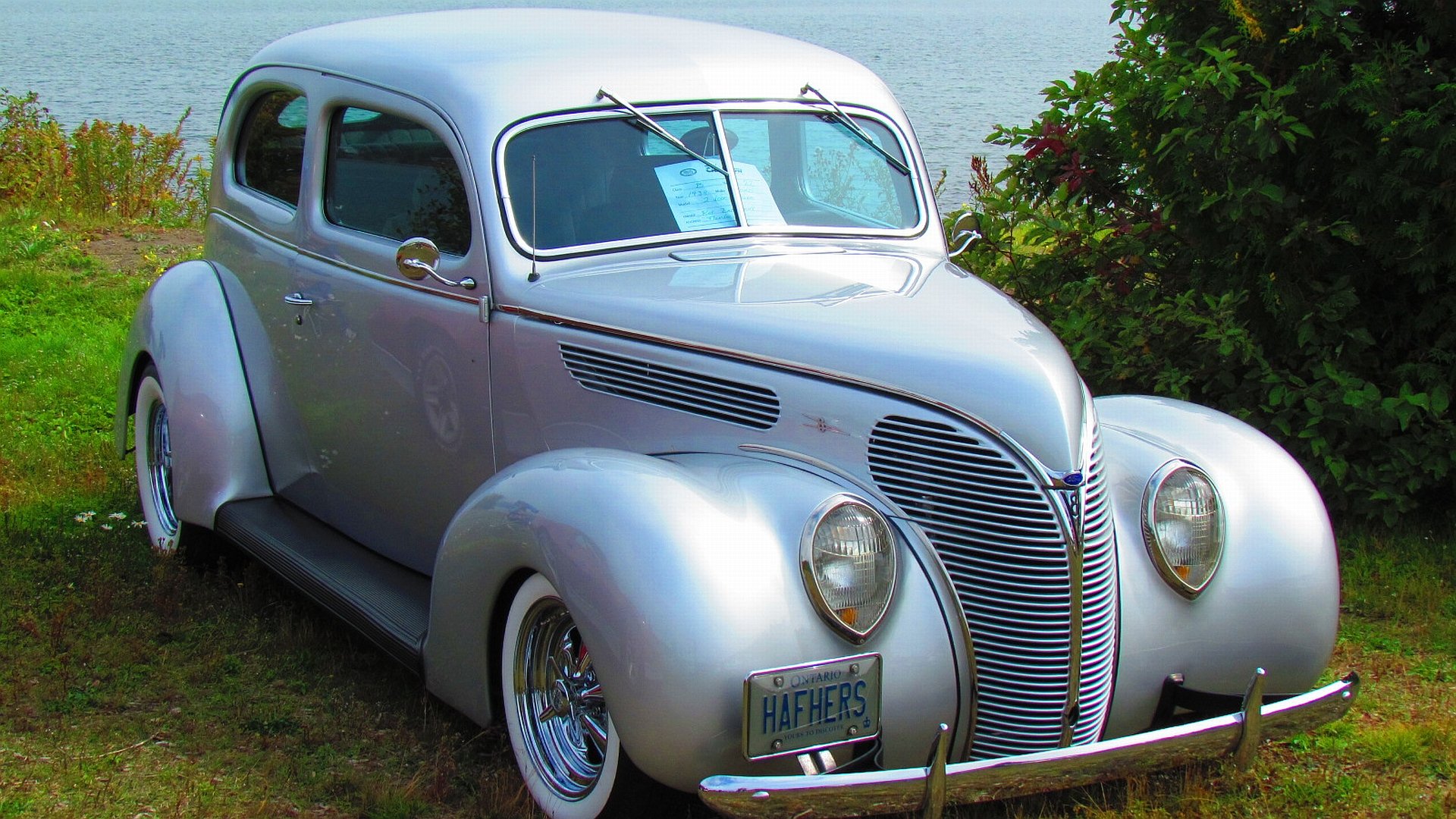 A vintage silver Ford Coupe parked on grass near water, showcased as an HD PC desktop wallpaper and background.