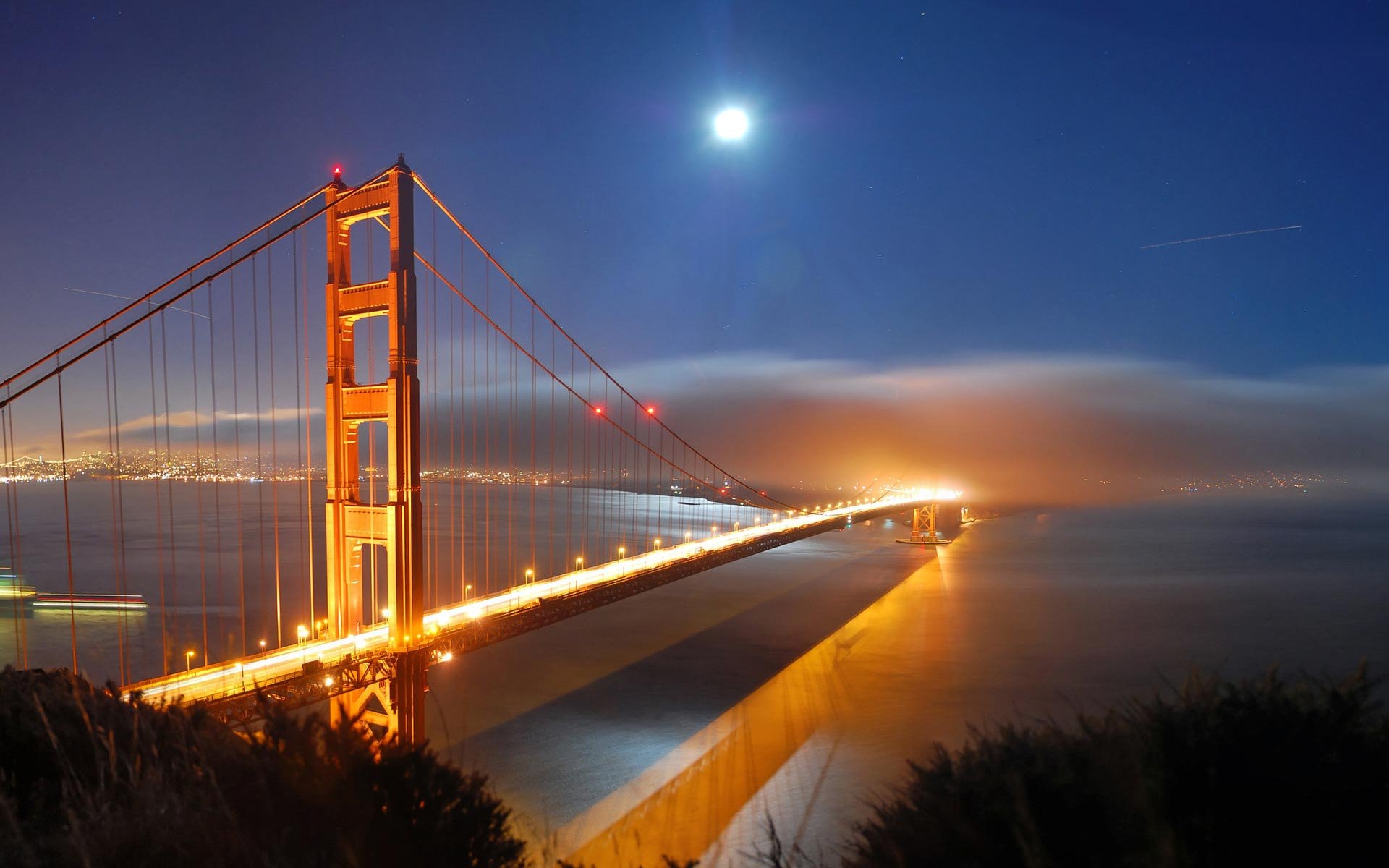 HD PC desktop wallpaper background: man-made Golden Gate Bridge at night, glowing lights and moon above with fog rolling over the water.