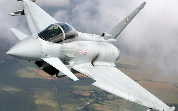 HD PC desktop wallpaper showing a military Eurofighter Typhoon soaring over patchwork countryside beneath a cloudy sky.