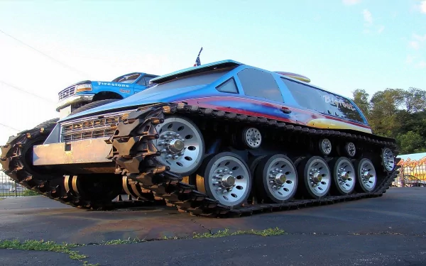 HD desktop wallpaper featuring a colorful monster truck with large wheels and tank-like tracks, set against an outdoor background.