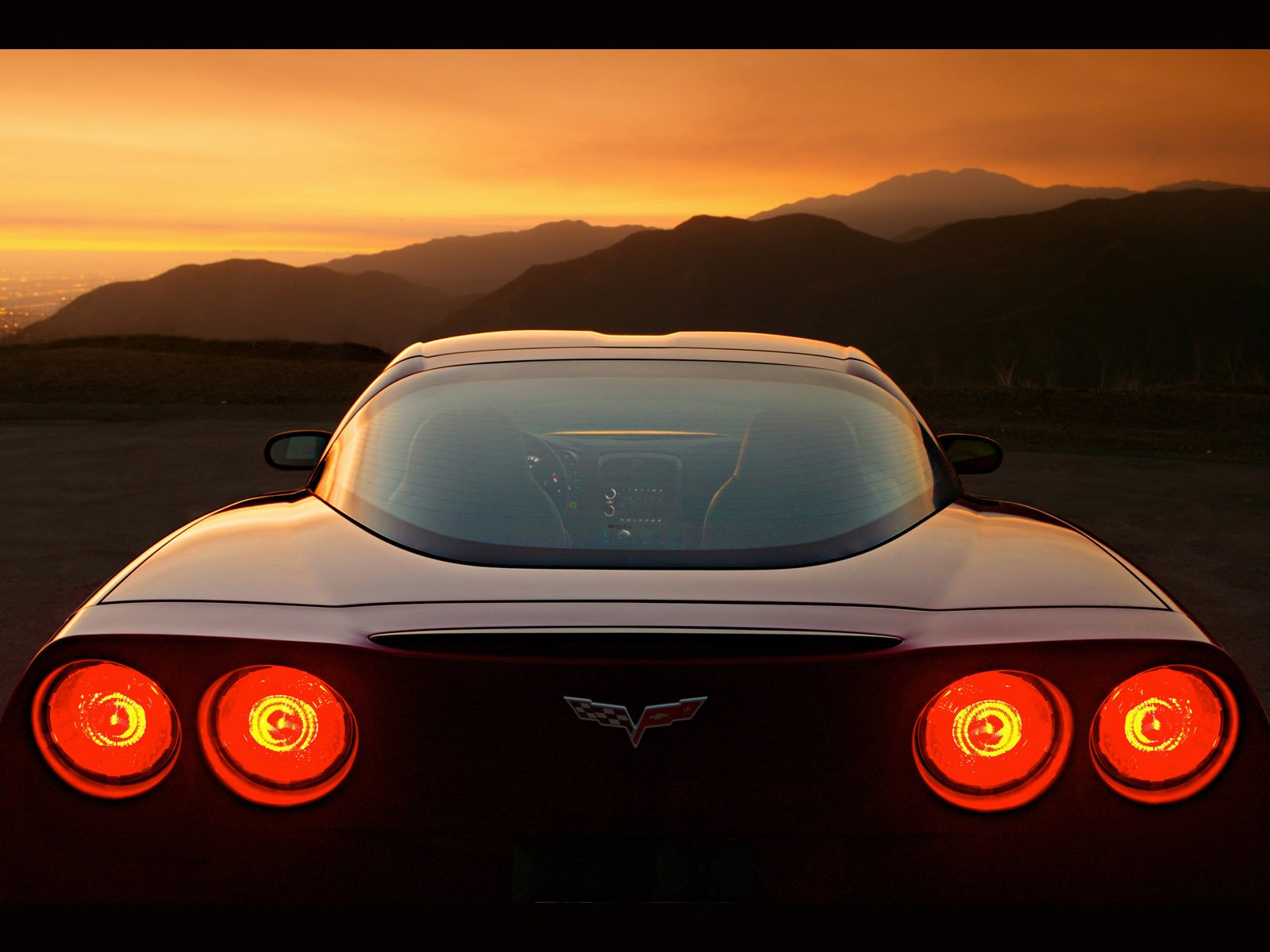 Red Corvette speeding on a scenic road.