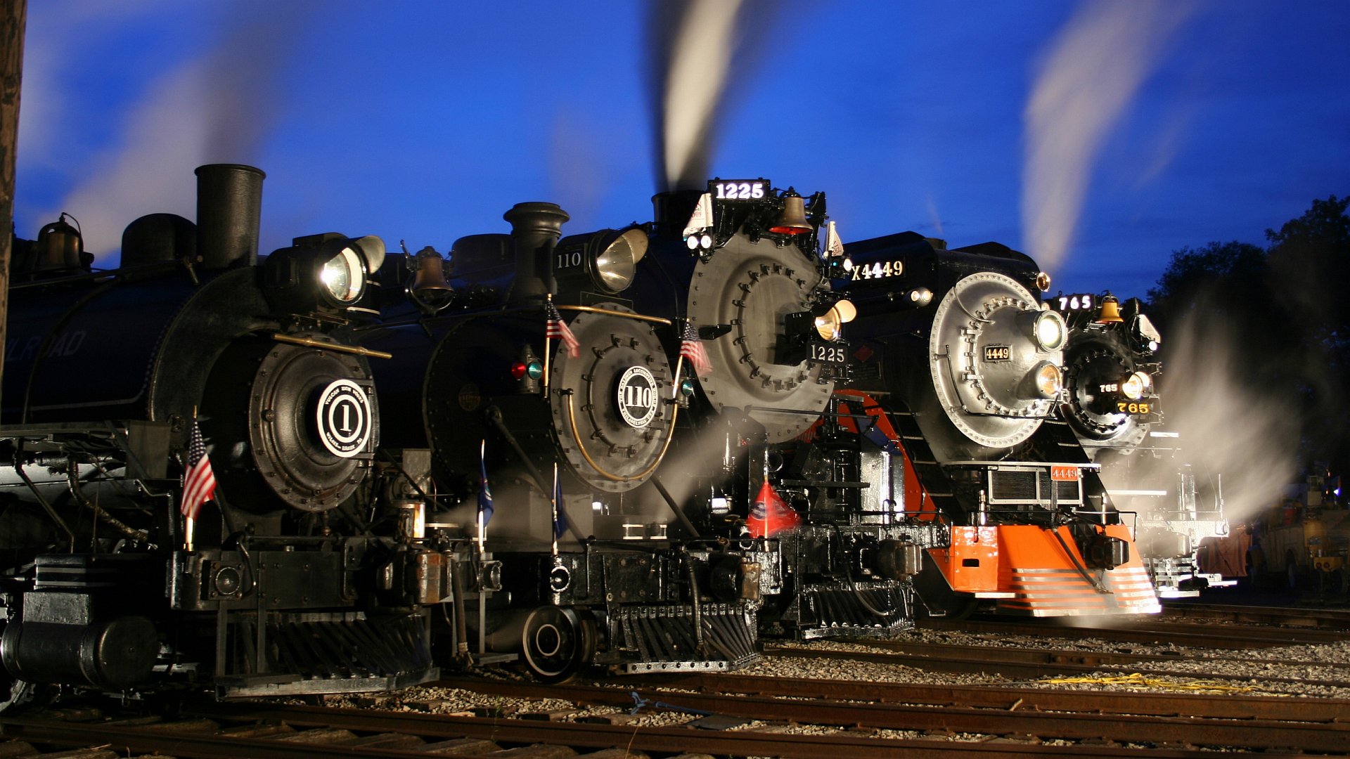 4K Ultra HD PC desktop wallpaper: three vintage steam train vehicles lined on tracks at night, glowing headlights and billowing steam under a deep blue sky.