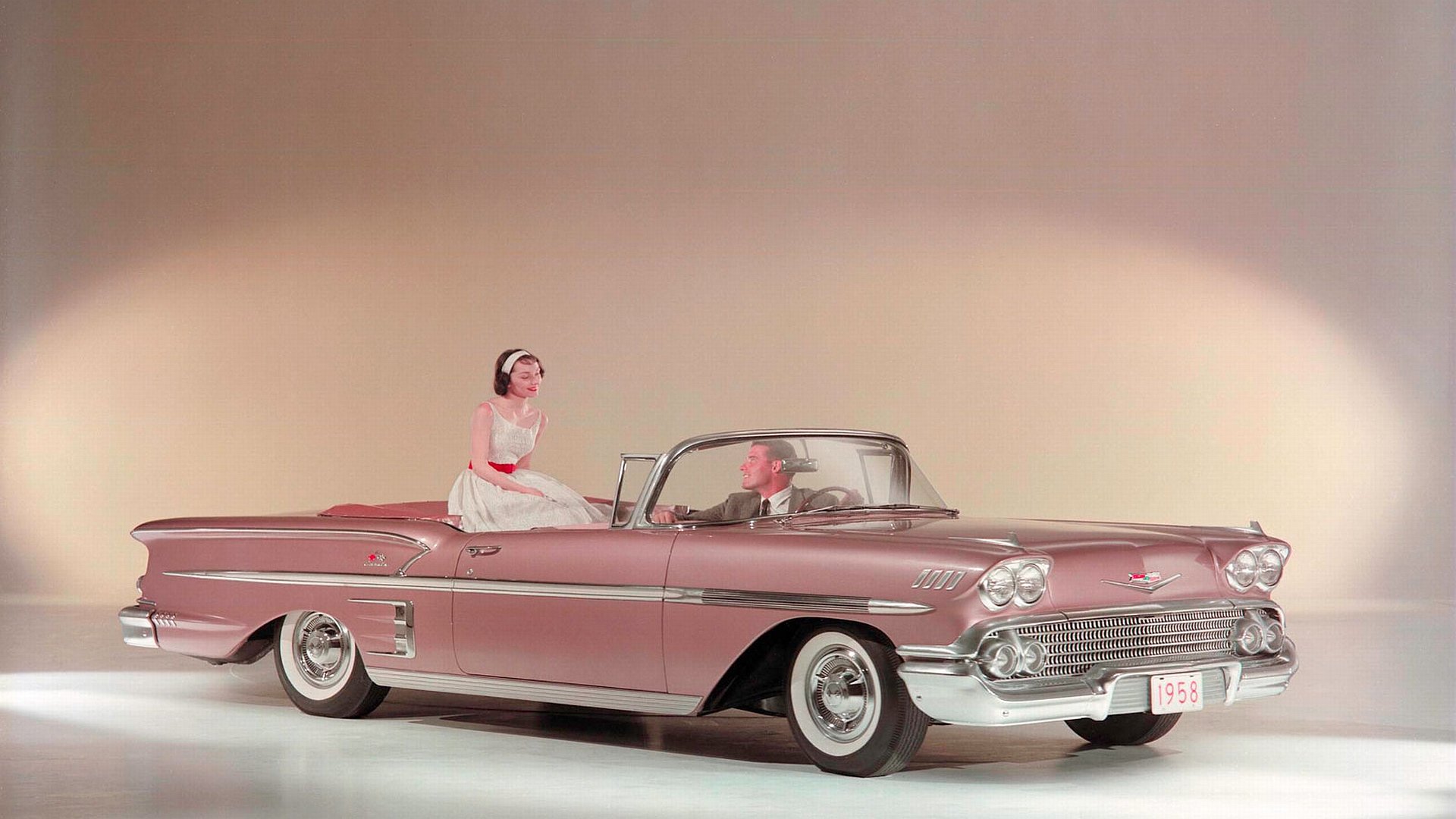 HD PC desktop wallpaper featuring a vintage pink convertible car with a woman in a retro outfit, blending classic automotive style and feminine elegance.