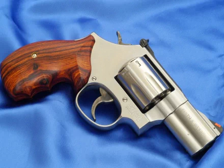 Man-made Smith & Wesson revolver with polished steel frame and rosewood grips resting on blue satin, presented as an HD PC desktop wallpaper and background.