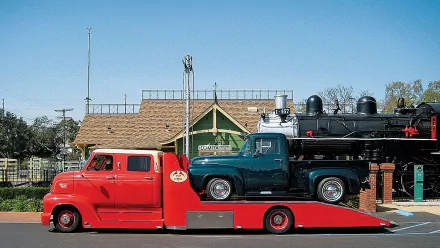 HD PC desktop wallpaper featuring a vintage red Ford car hauler transporting a classic green Ford pickup truck with a steam locomotive in the background.