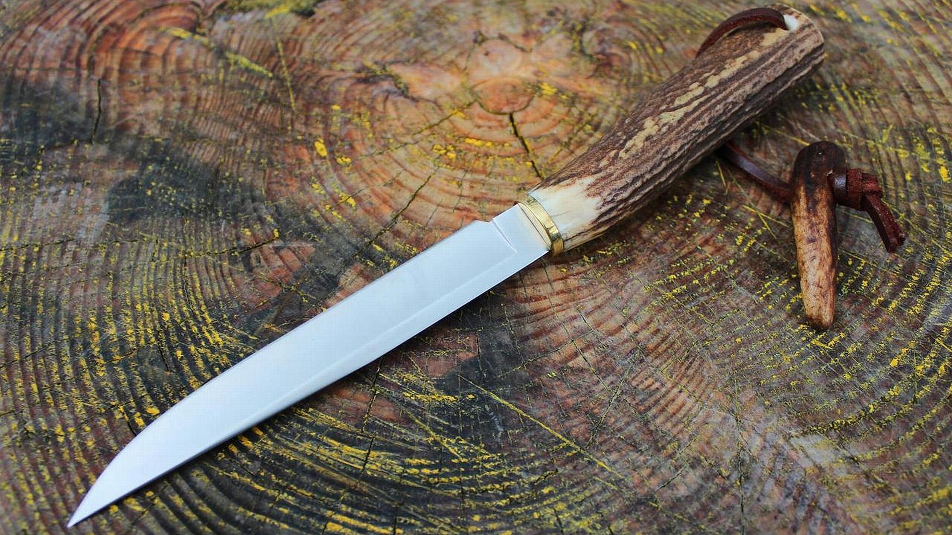 A beautifully crafted knife with a wooden handle resting on a textured tree stump, serving as an HD desktop wallpaper and background.