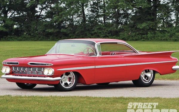 HD desktop wallpaper featuring a classic red Chrysler vehicle parked on a paved road with green trees in the background.