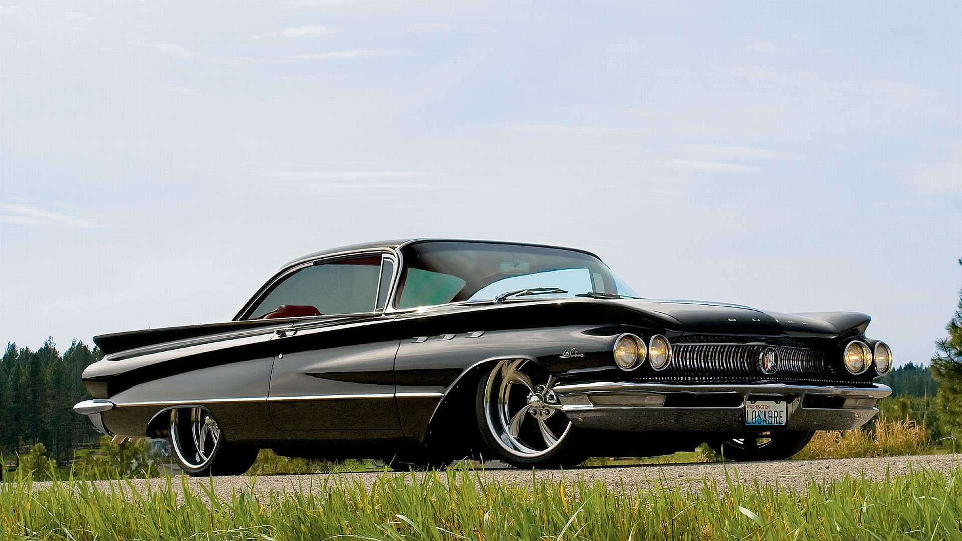 HD desktop wallpaper featuring a sleek black Buick vehicle parked on grass under a clear sky, highlighting its classic design and polished chrome details.