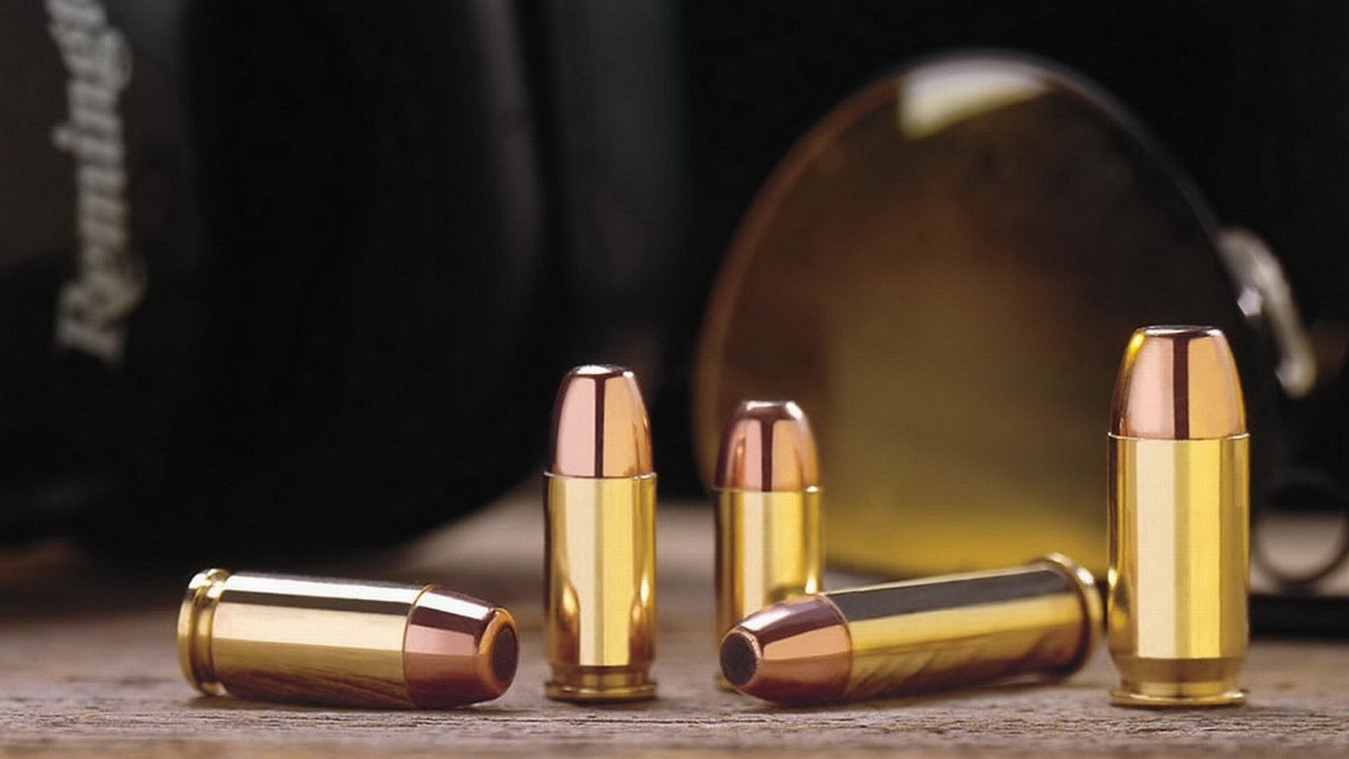 HD PC desktop wallpaper/background: man-made copper-and-brass bullets arranged on a wooden surface, shallow depth of field with warm, glossy reflections.