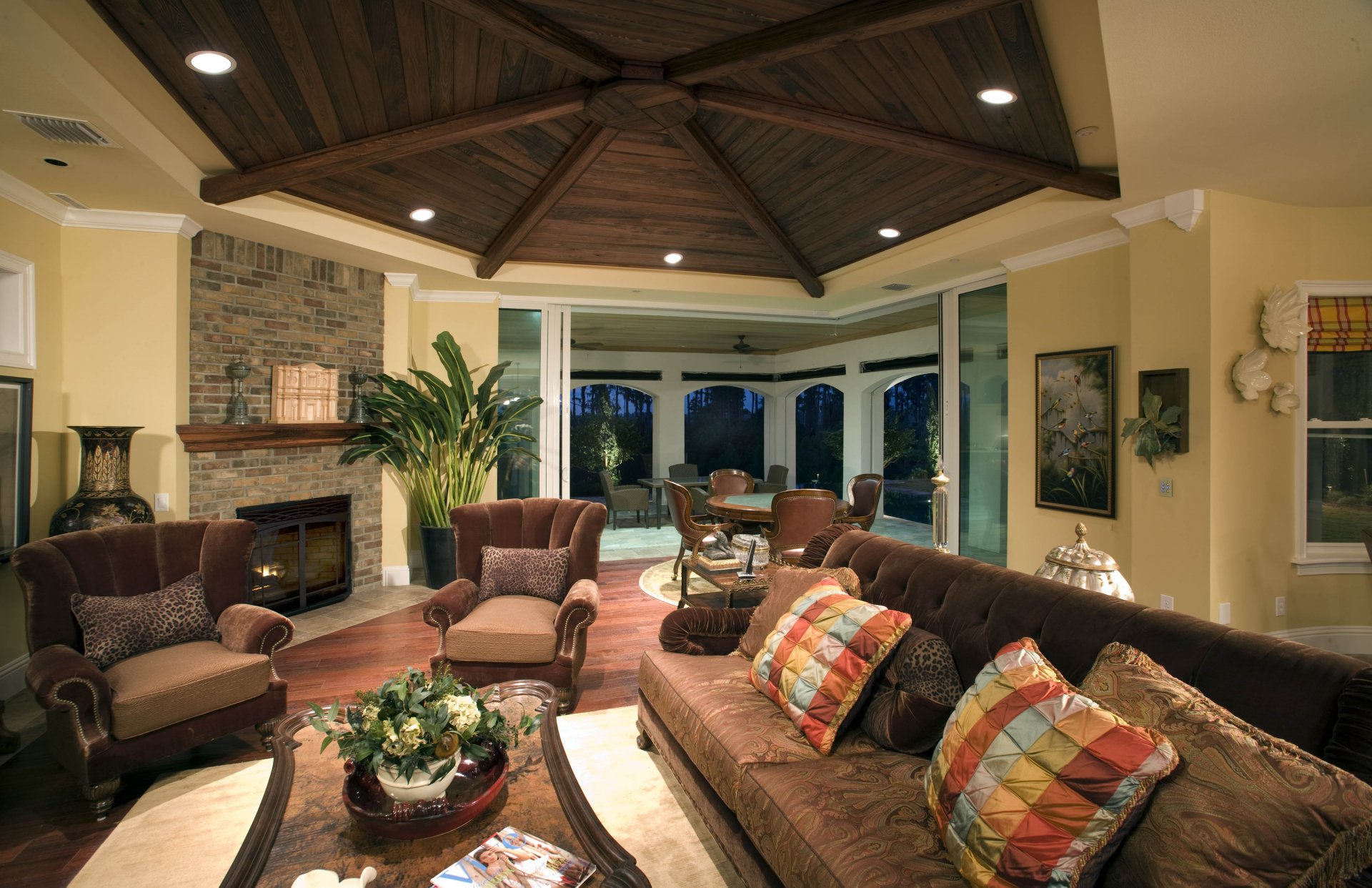 Cozy cottage living room with a fireplace, plush chairs, and a comfortable lounge area under a wooden beamed ceiling, captured in 4K Ultra HD.
