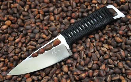 A sleek knife rests on a bed of roasted coffee beans, showcasing its polished blade and intricate handle, making for an striking HD PC desktop wallpaper and background.