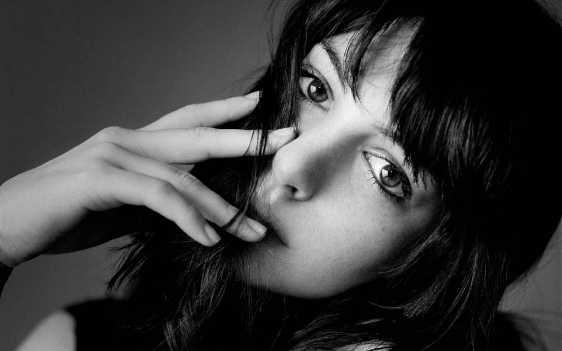 A high-definition black and white wallpaper featuring a close-up of actress Anne Hathaway, showcasing her expressive eyes and thoughtful gesture.