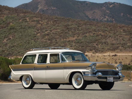 A beige vintage Packard Clipper Country Sedan station wagon parked on a road with hills in the background, captured as an HD PC desktop wallpaper.