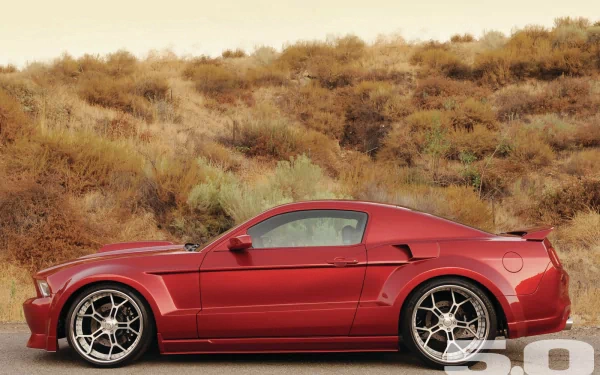 HD PC desktop wallpaper featuring a red Ford sports car parked in front of a dry, shrub-covered hillside.