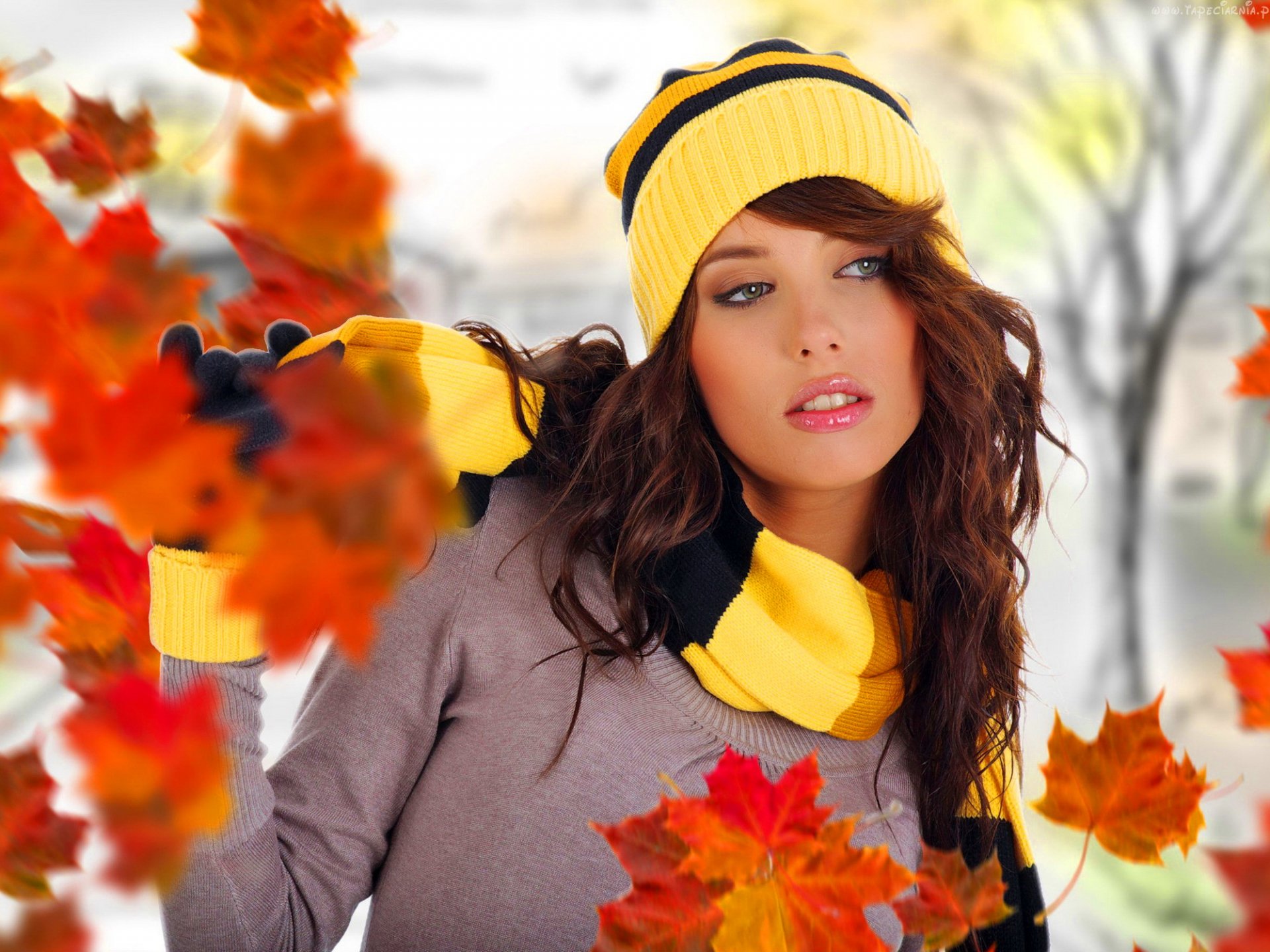 HD PC desktop wallpaper of a woman model wearing a yellow beanie and scarf, surrounded by vibrant autumn leaves in a soft-focused outdoor setting.