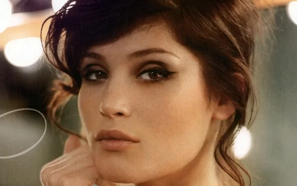 Gemma Arterton poses elegantly, showcasing her striking features against a backdrop of soft lights. This image serves as a captivating HD desktop wallpaper.