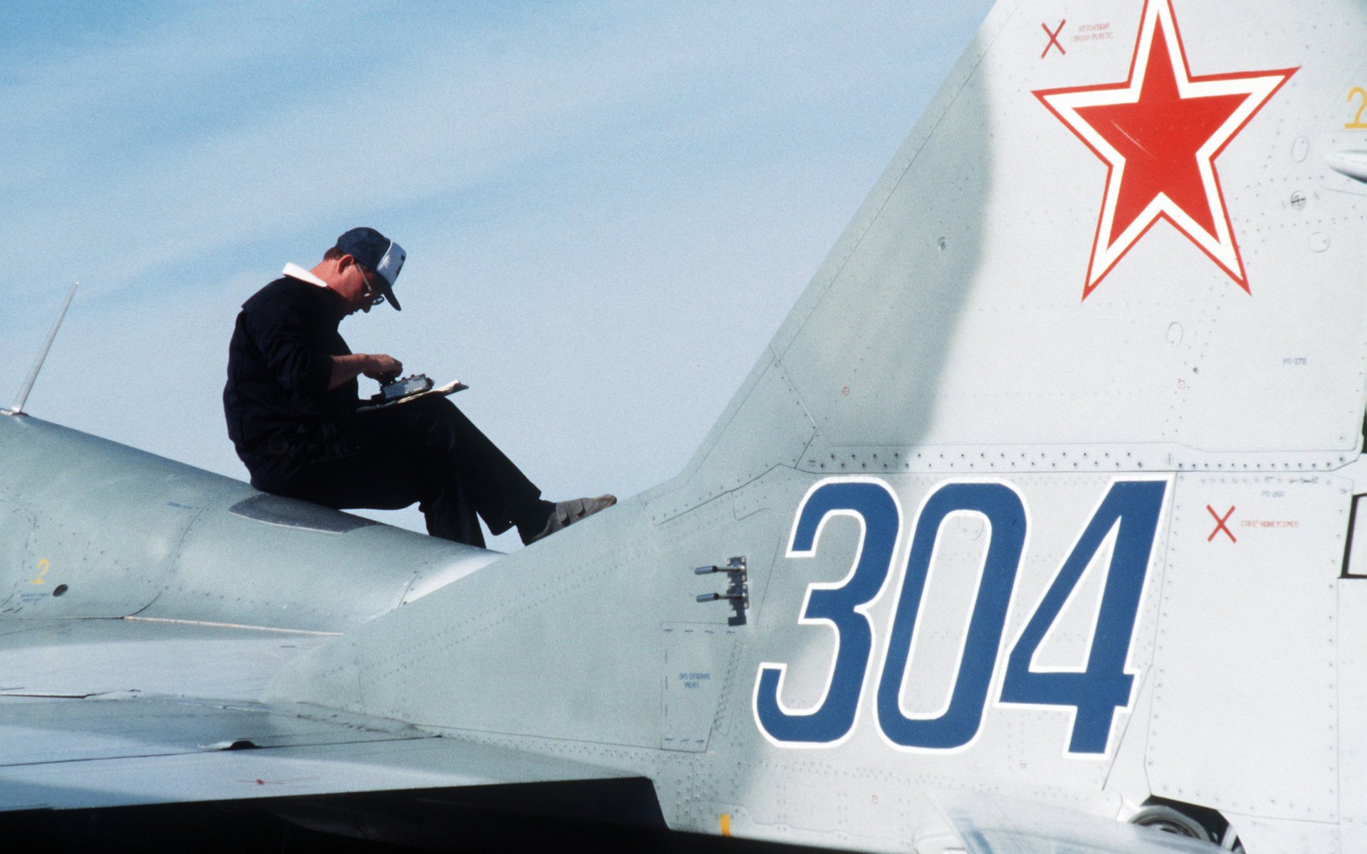 A technician works on the tail of a military aircraft, showcasing detailed markings and the vibrant star insignia, set against a clear sky—an engaging HD PC desktop wallpaper.