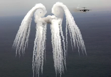 A Boeing C-17 Globemaster III aircraft releases vapor trails, creating an artistic cloud formation above the ocean, showcased as a stunning military-themed HD desktop wallpaper.