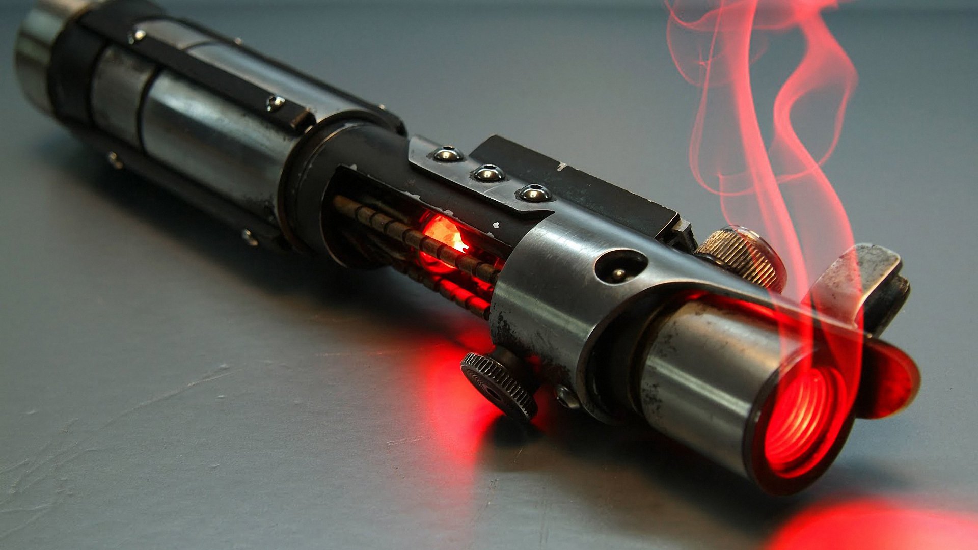 A dynamic HD desktop wallpaper featuring a Star Wars lightsaber, showcasing glowing red details and wisps of steam, bringing a touch of sci-fi adventure to your background.